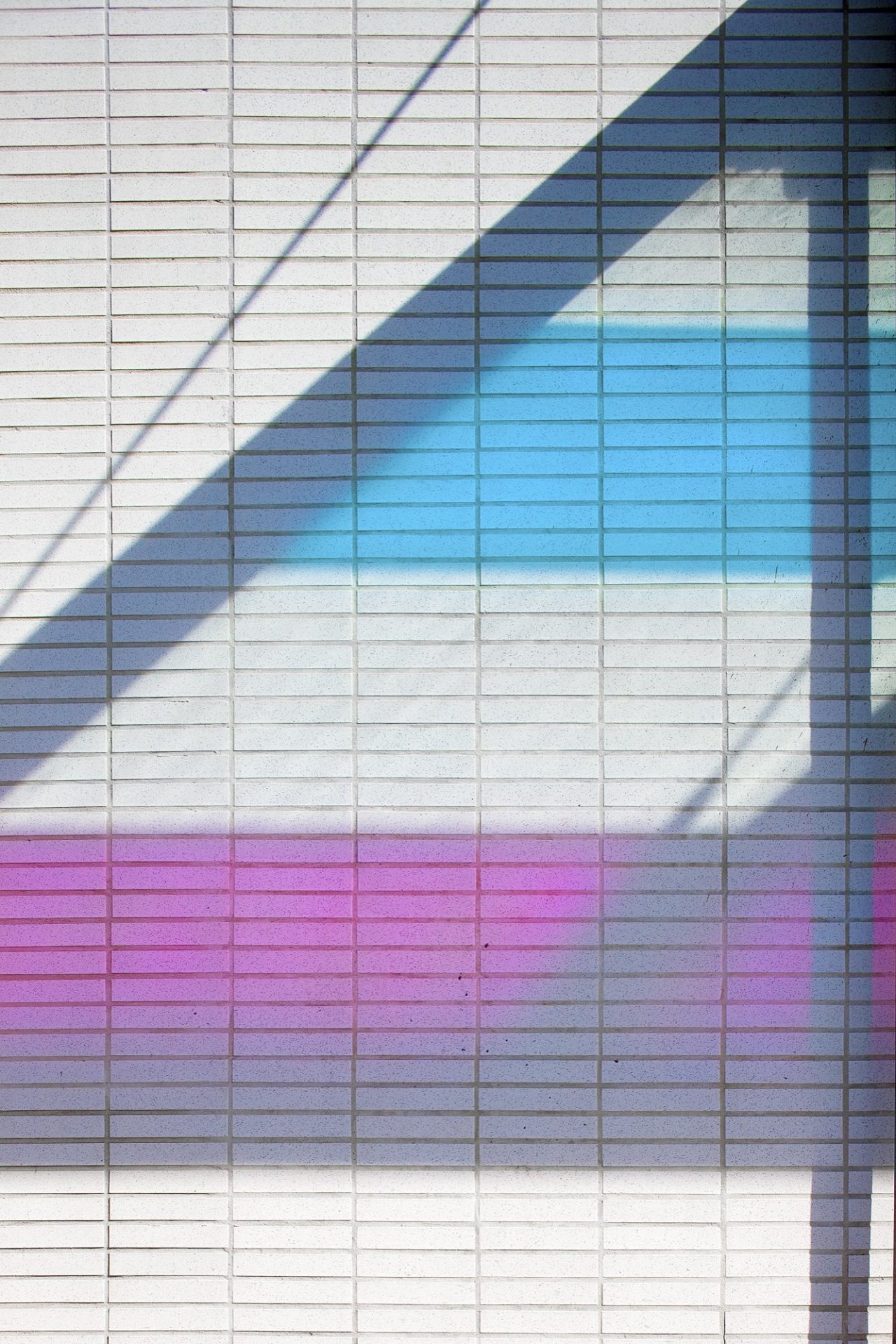 wash of coloured light on white-brick wall.